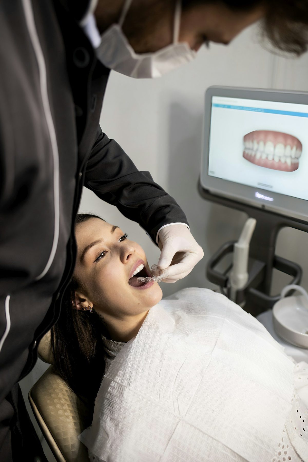 Dentist fitting a clear aligner for a smiling patient