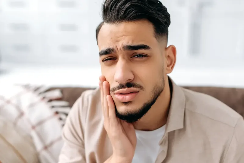 Man holding his jaw in tooth pain